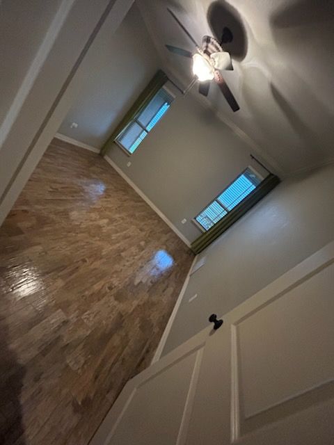 A bedroom with hardwood floors and a ceiling fan.