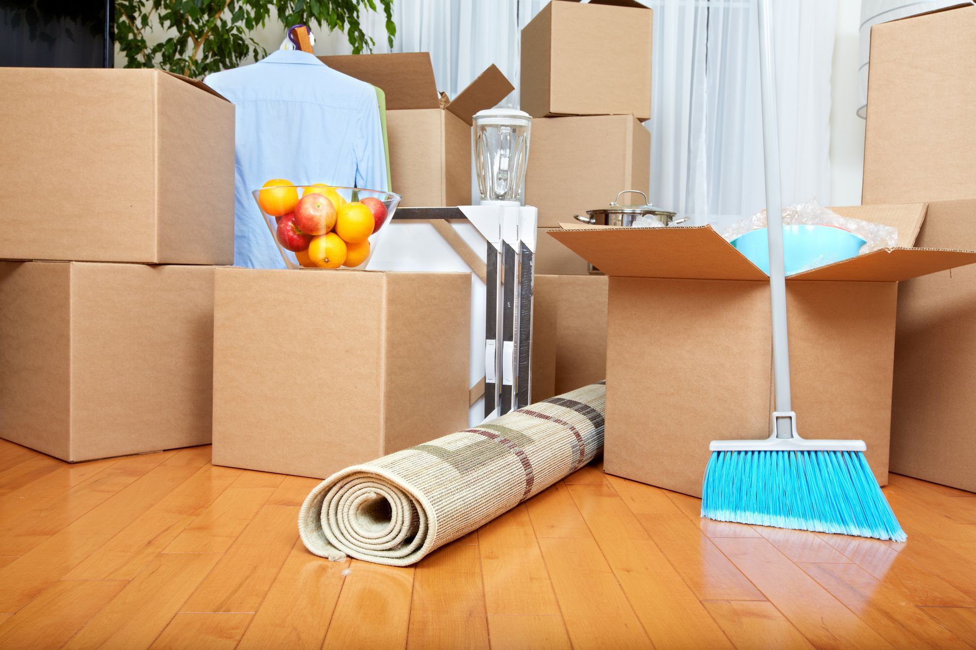 A room filled with cardboard boxes and a broom