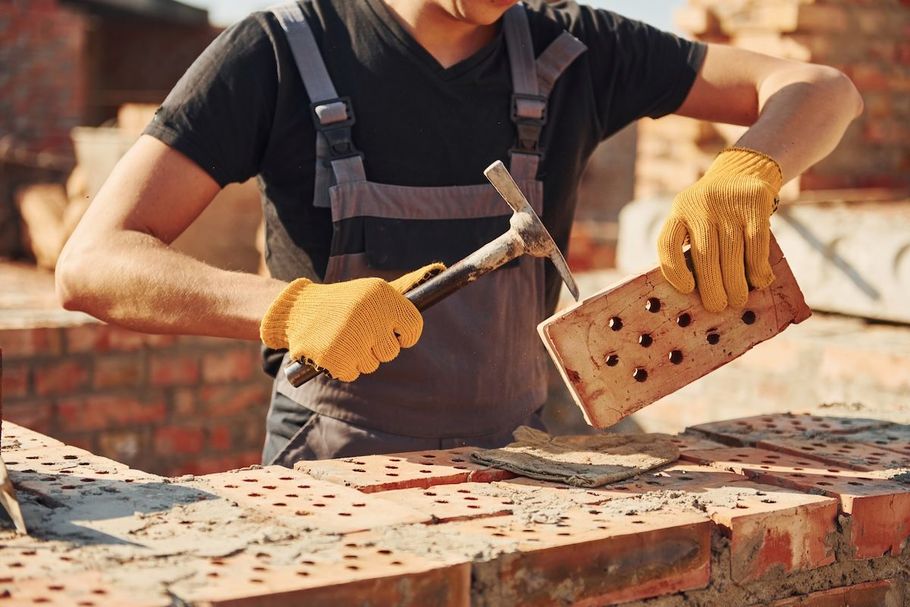 Construction worker laying bricks with a trowel and mortar on a brick wall