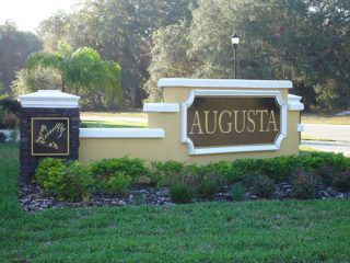 A sign for augusta is in the middle of a lush green field.