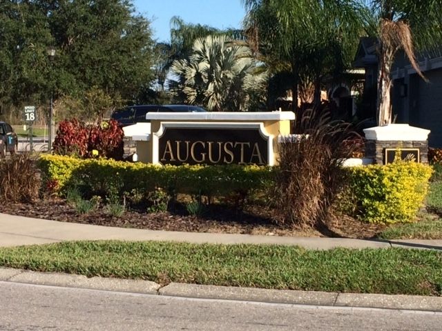 A sign for augusta is in the middle of a lush green field.