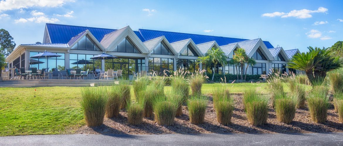 A large building with a blue roof is surrounded by grass and trees.