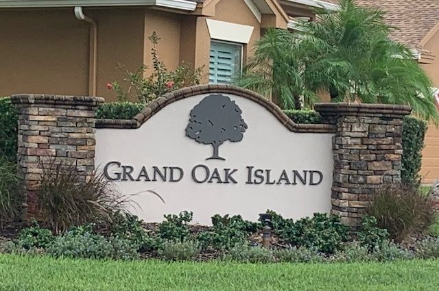 A sign for grand oak island with a tree on it