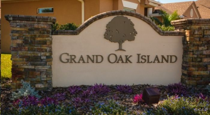 A sign for grand oak island with a tree on it