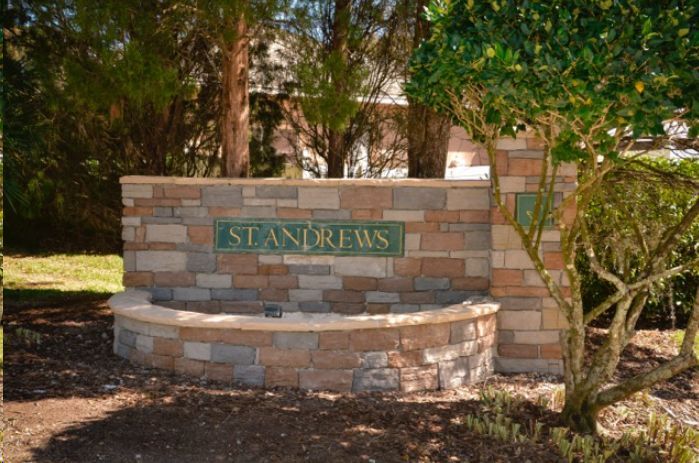 A stone wall with a sign that says ' standrews ' on it