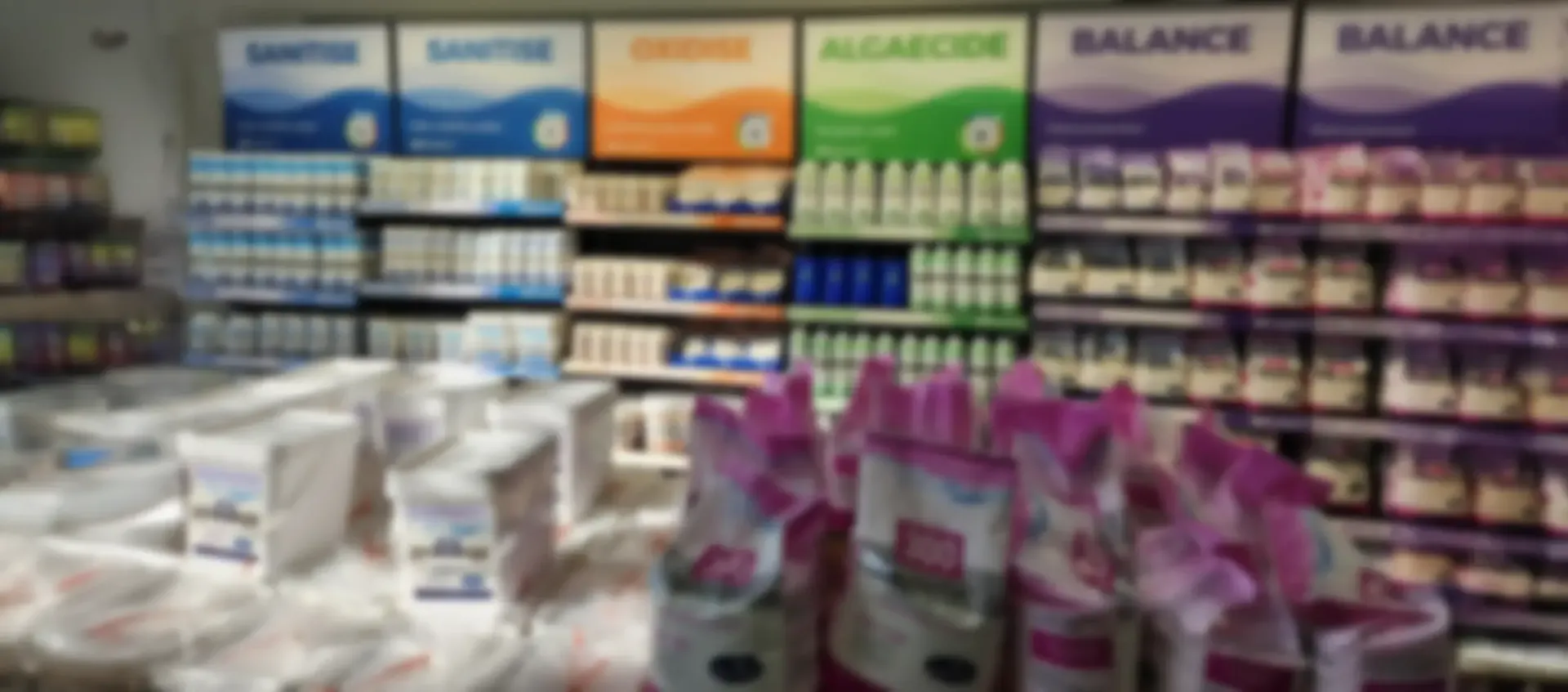 Shelves of pet food and supplies in a store. Signs for different brands are above the shelves.