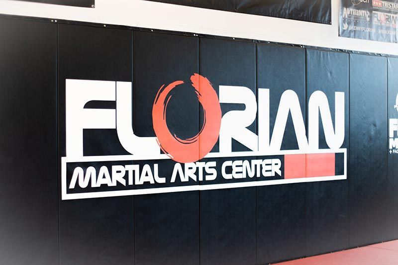 Florian Martial Arts Center sign on a black wall, white and orange lettering