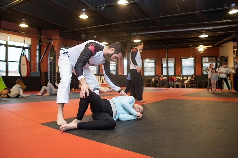 Brazilian jiu-jitsu sparring on orange mats in an indoor training gym