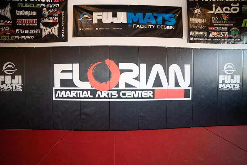 Florian Martial Arts Center wall with black matting, red floor, and sponsor banners above