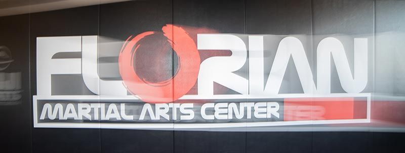 Florian Martial Arts Center sign in white and red on a dark storefront background