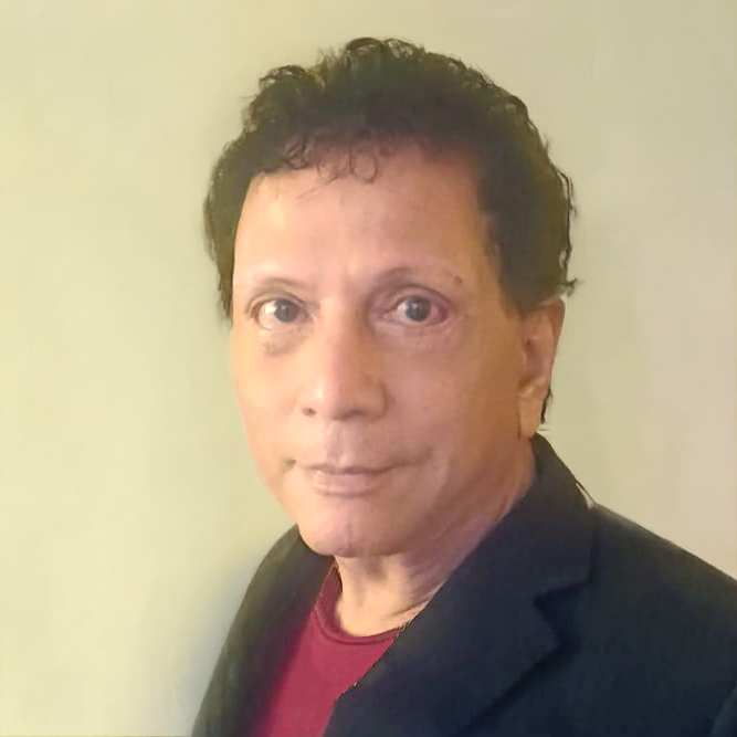 Man with short dark hair wearing a black jacket over a red shirt, looking at the camera.