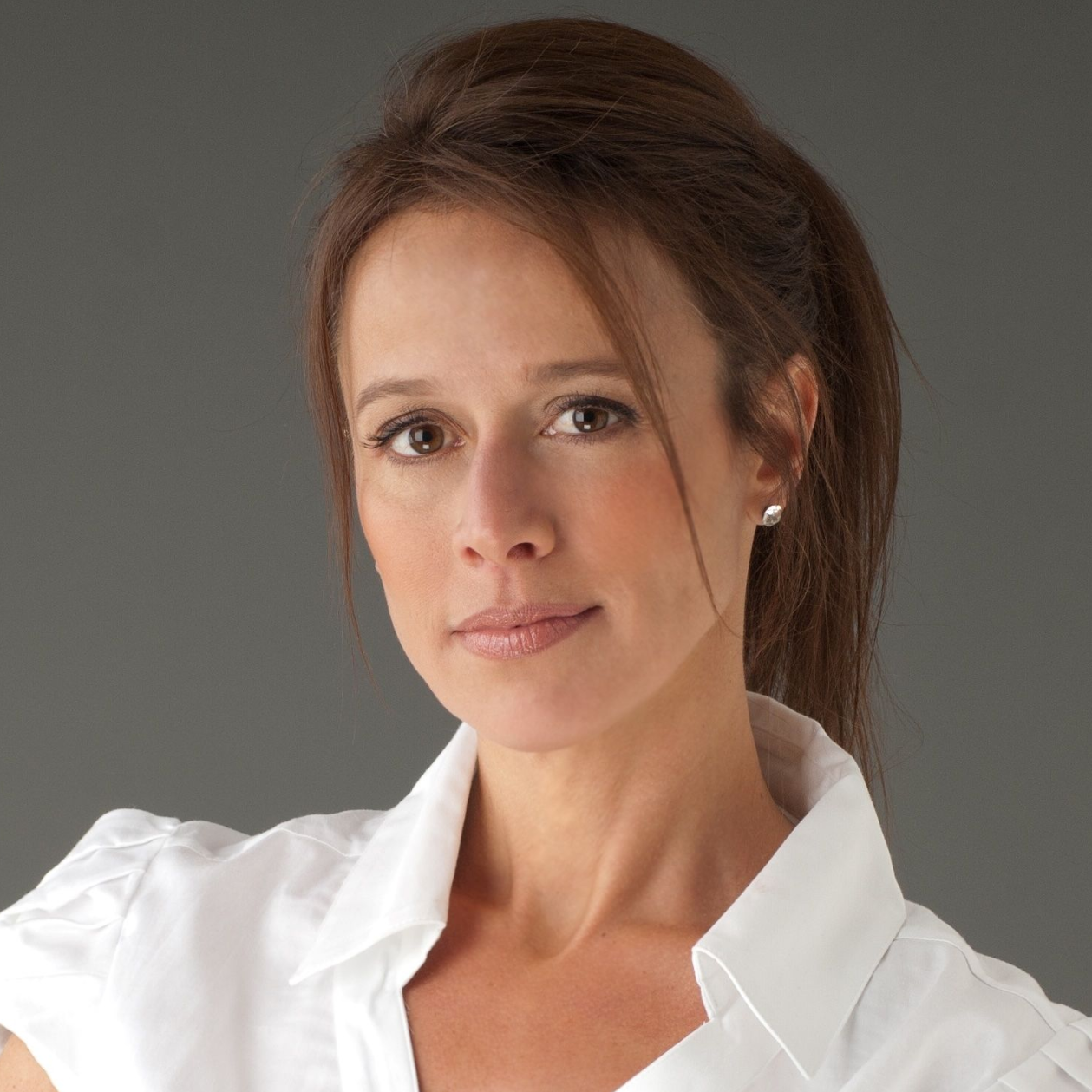 Woman with brown hair in a white shirt, looking at the viewer, neutral expression, studio shot.