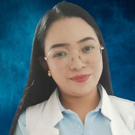 Woman with glasses and dark hair, wearing a light blue shirt and white coat, smiles against a blue background.
