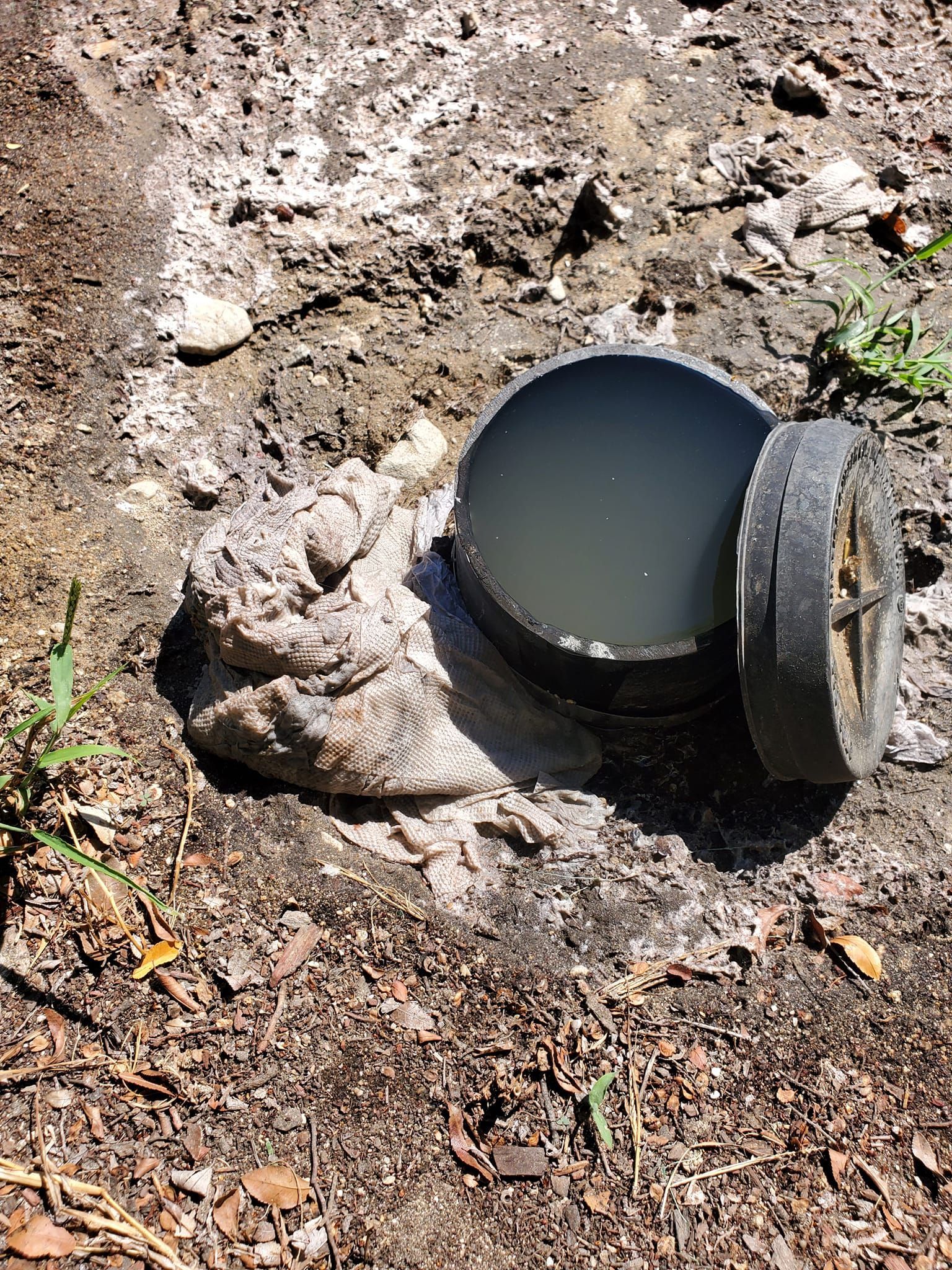 A muddy pipe is sitting on top of a pile of dirt.