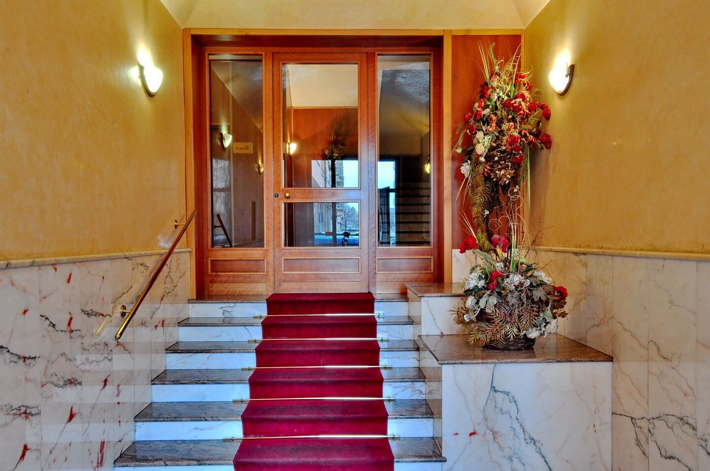 Una scala con un tappeto rosso e un vaso di fiori