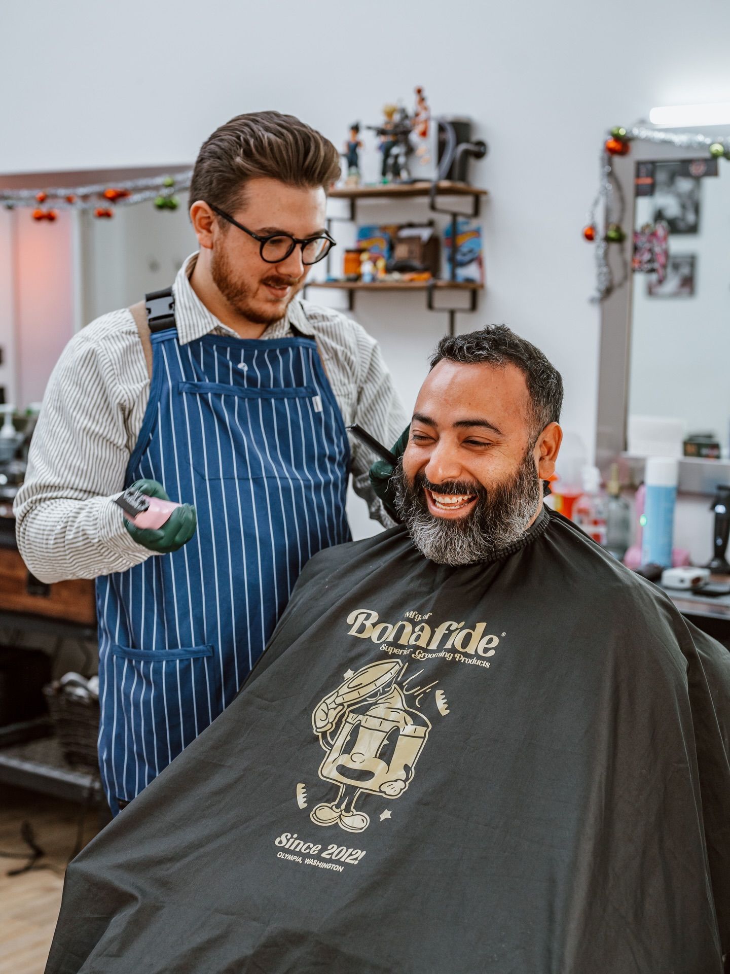 Barber giving a haircut to a smiling client in a barbershop.