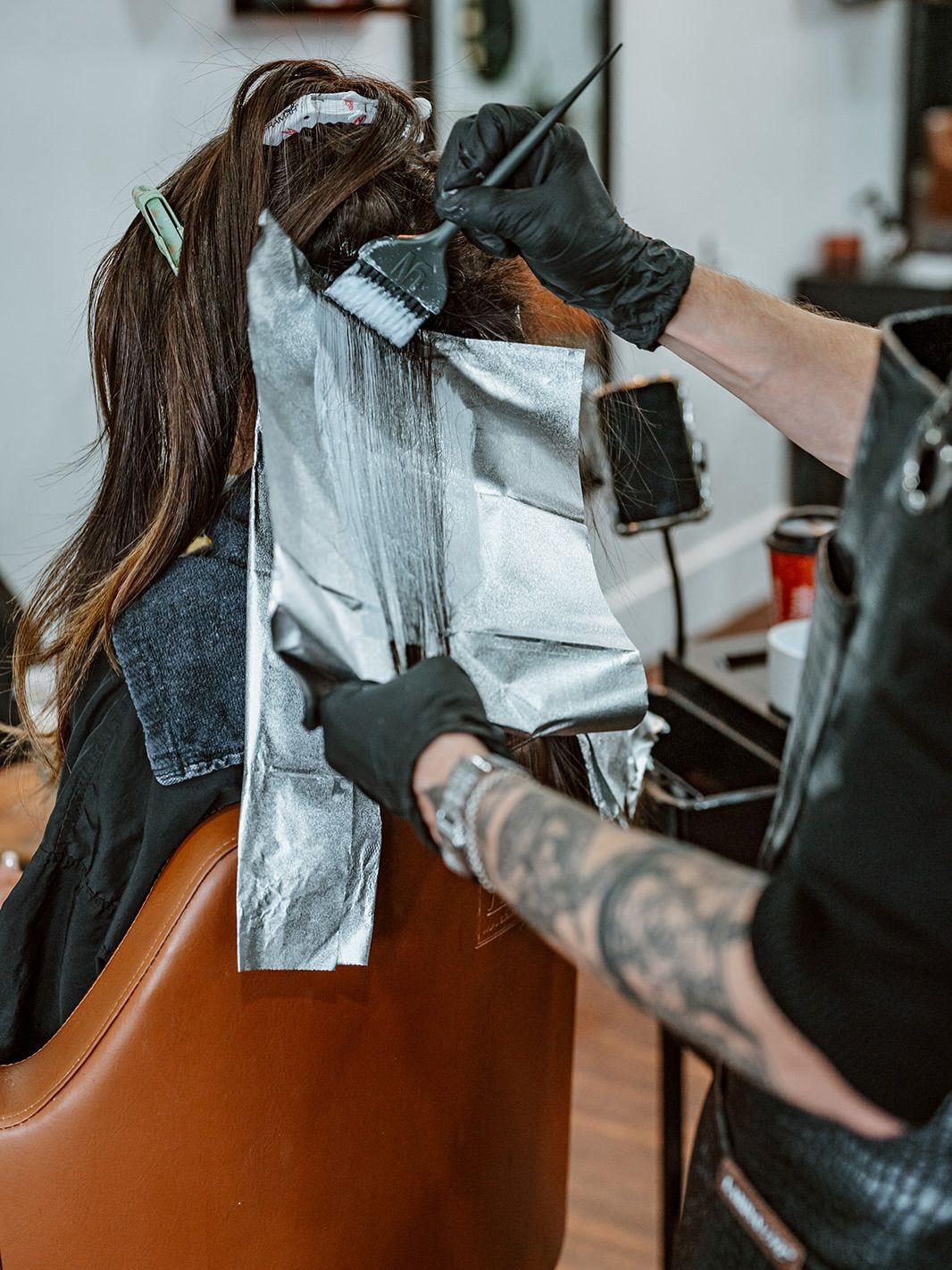 Person having hair dyed at a salon; stylist applying color with brush and foil.