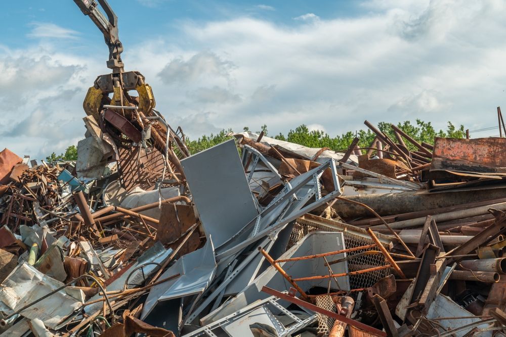 Excavator amid a pile of demolished building debris under a blue sky