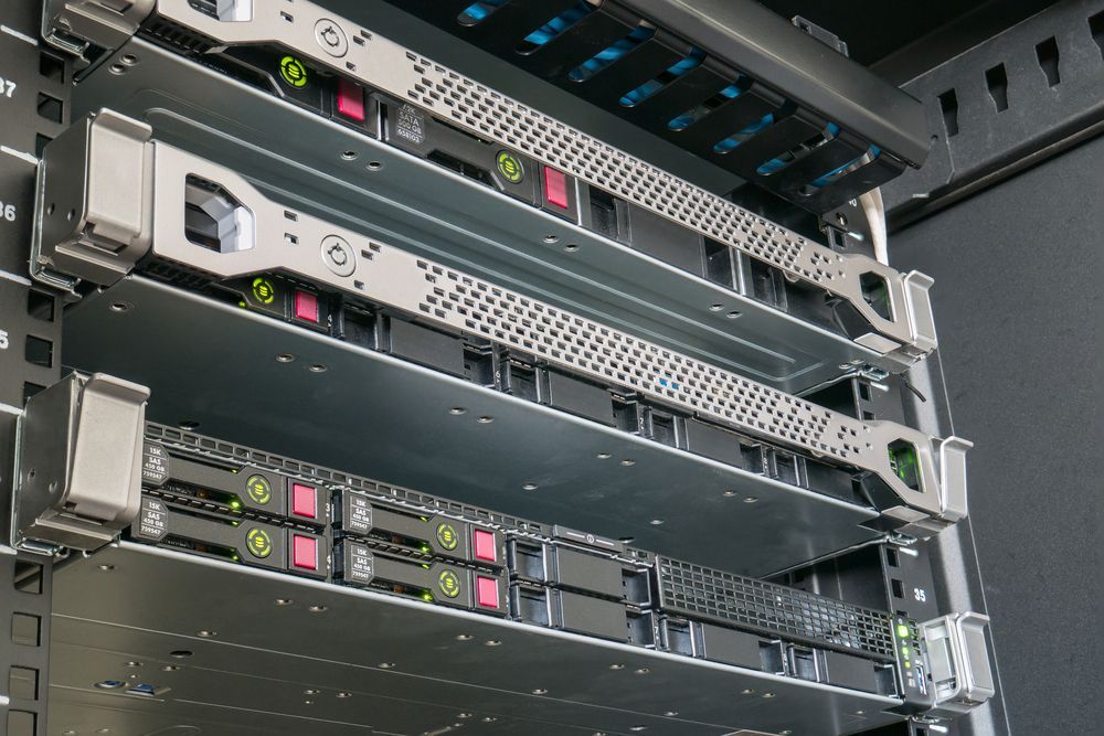 Server rack with stacked silver and black rack-mounted equipment, indicator lights glowing in a data center