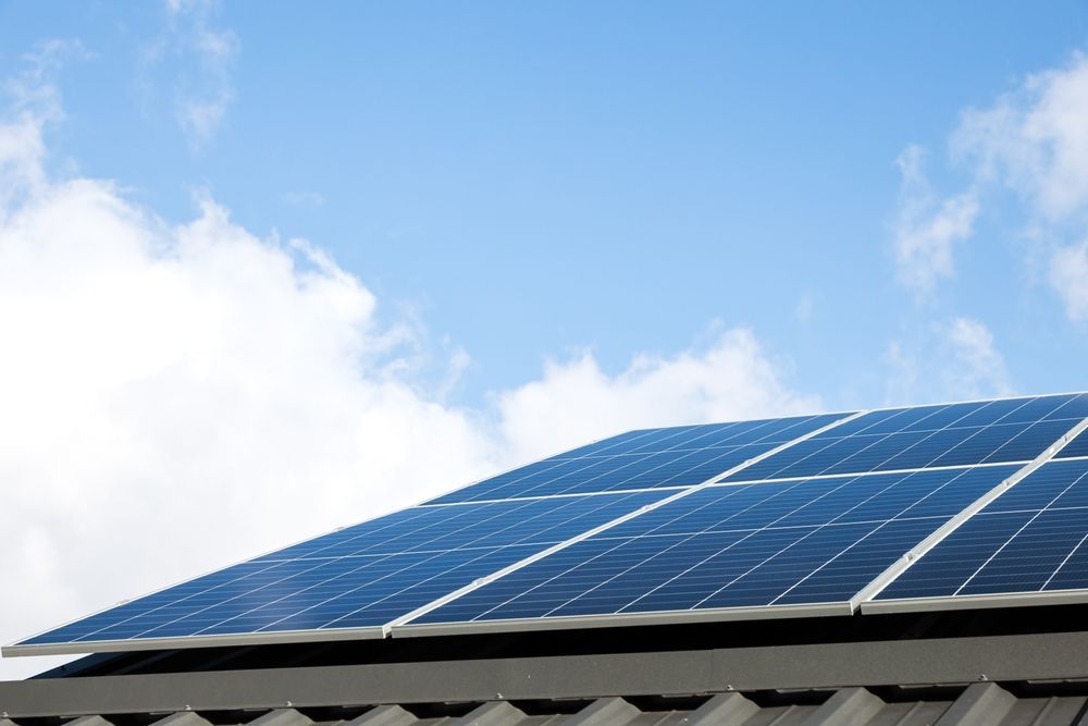 Solar panels on a rooftop against a blue sky with clouds