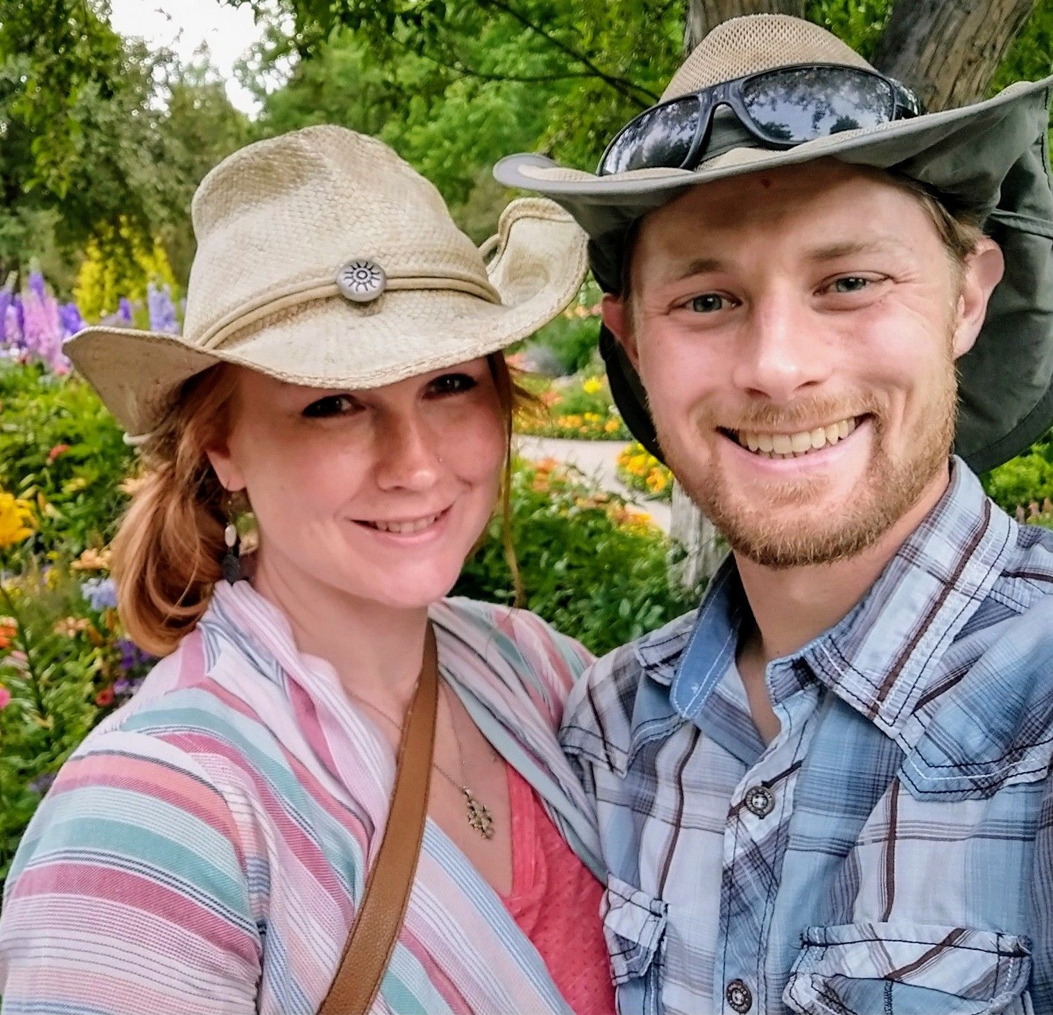 A man and a woman wearing cowboy hats and sunglasses are posing for a picture.
