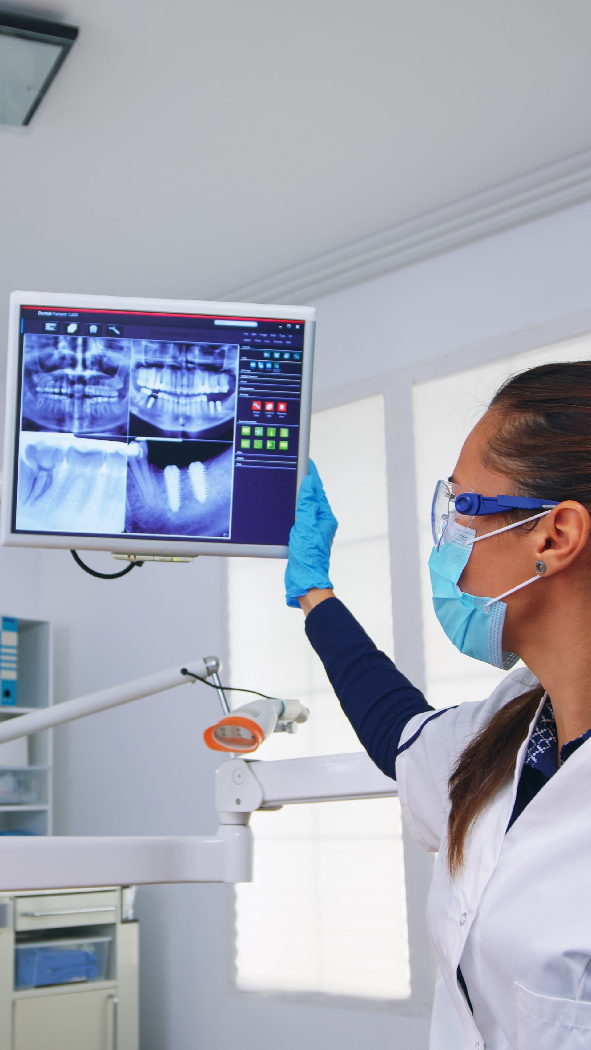 Una dentista está mirando una radiografía en la pantalla de una computadora.