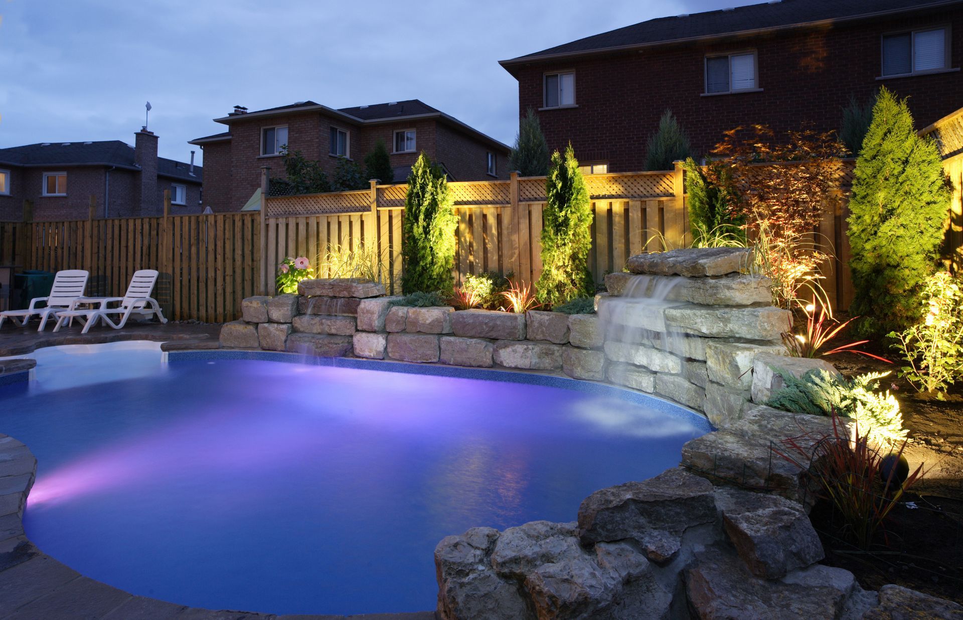 A swimming pool is lit up at night with purple lights