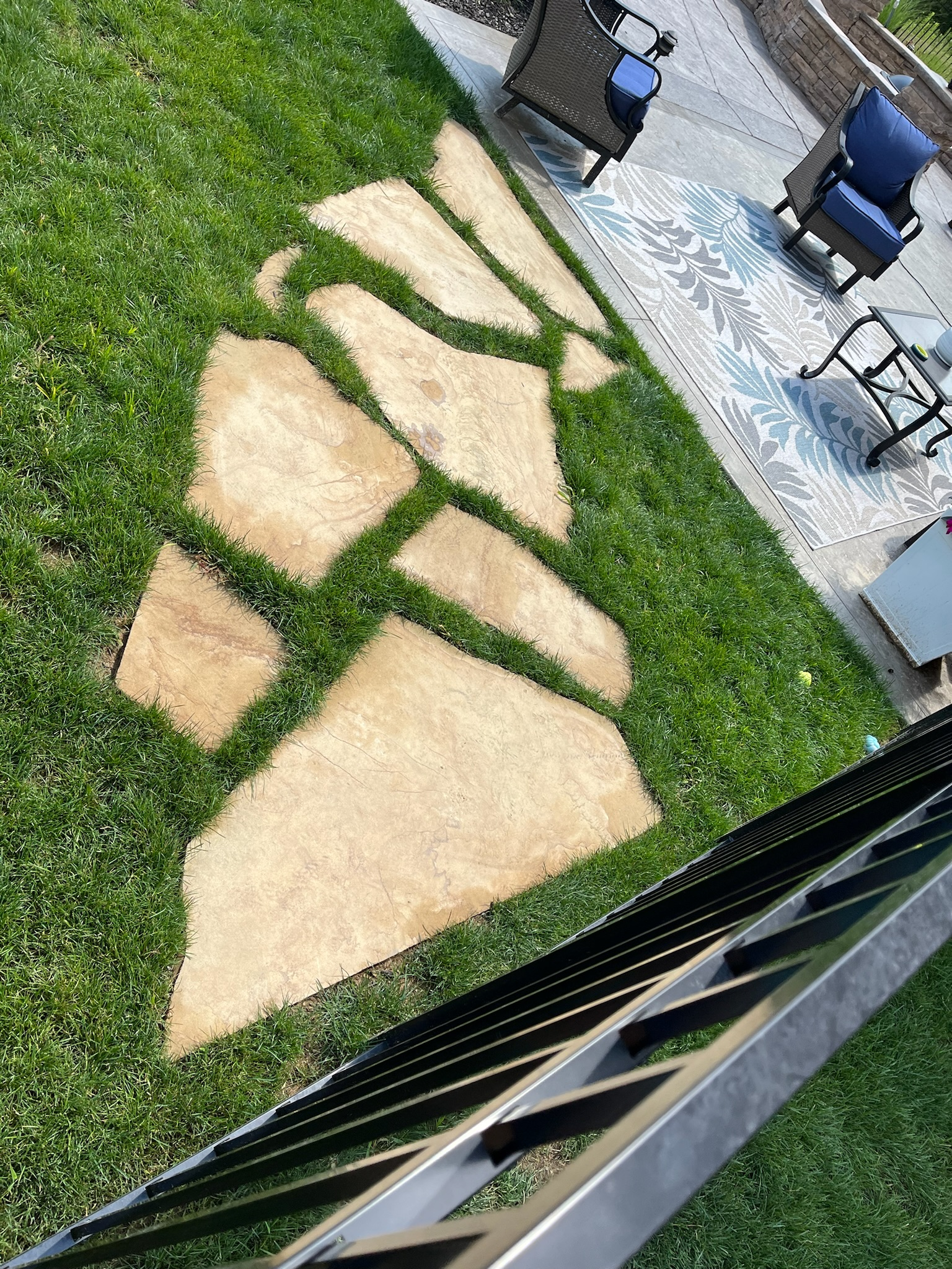 A stone walkway in the grass next to a patio.