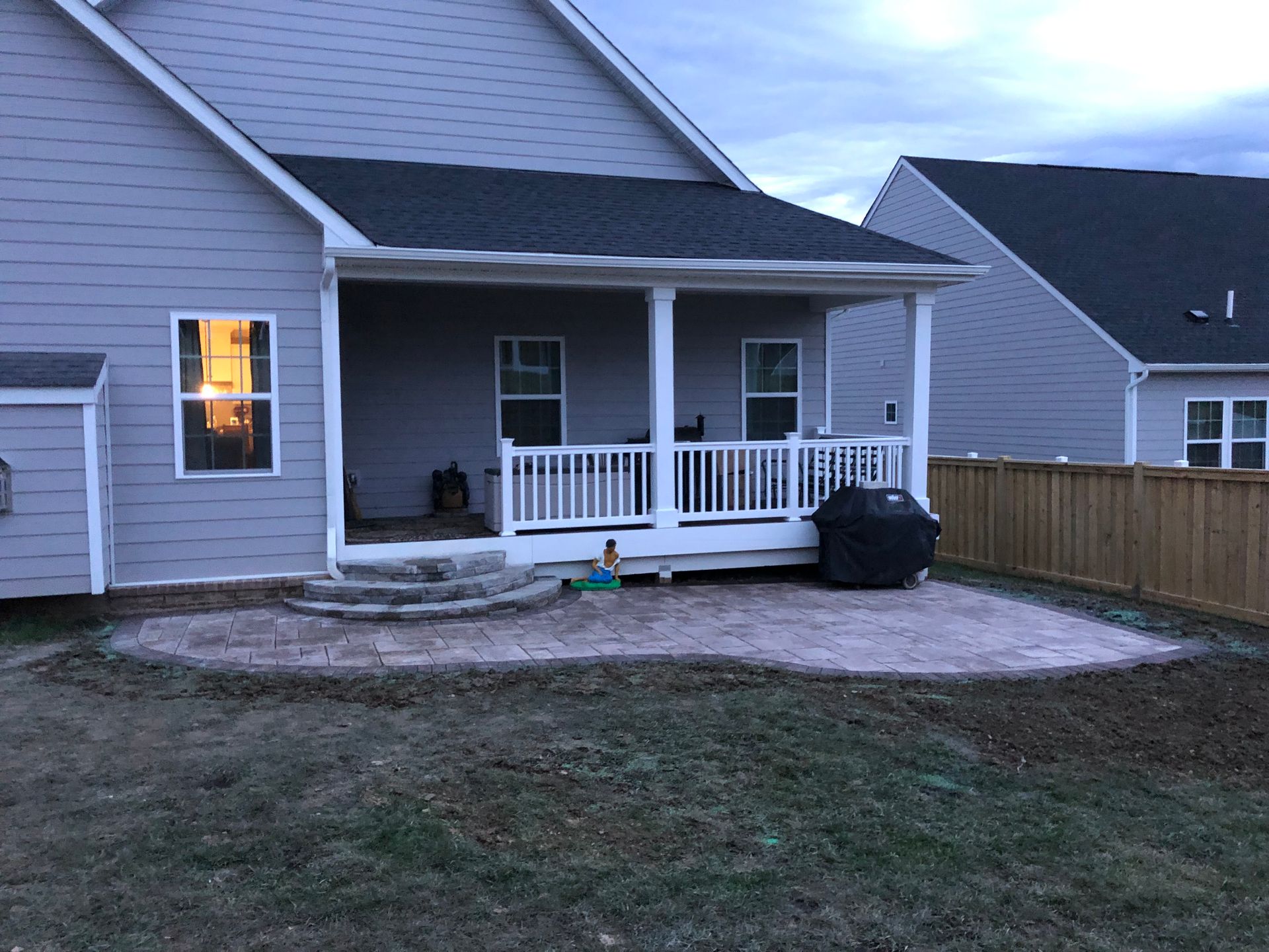 A house with a porch and a grill in the backyard.
