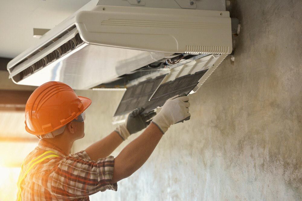 A Man Wearing A Hard Hat And Gloves Is Working — Jordan Wheatland Air Conditioning & Refrigeration In Dubbo, NSW