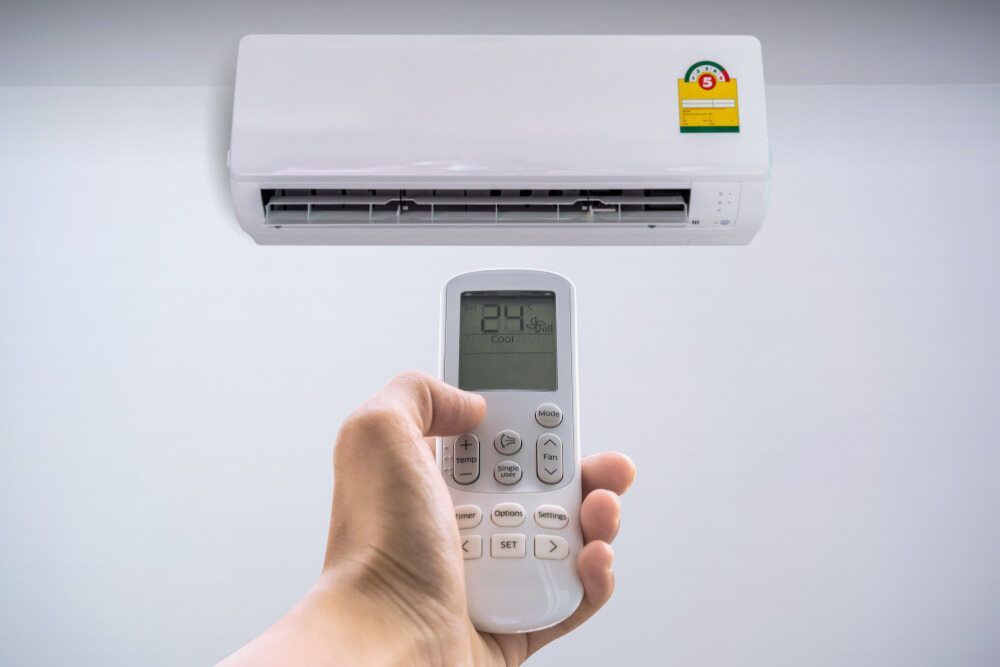 A Person Is Holding A Remote Control — Jordan Wheatland Air Conditioning & Refrigeration In Dubbo, NSW
