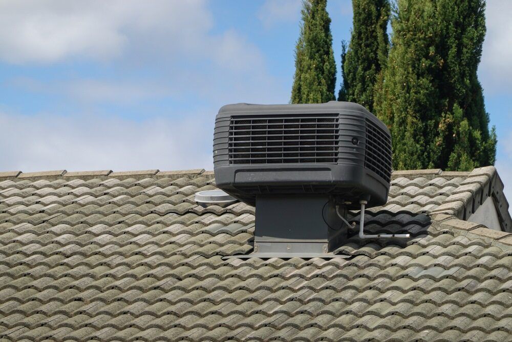 A Black Air Conditioner Is Sitting On Top Of A Tiled Roof — Jordan Wheatland Air Conditioning & Refrigeration In Dubbo, NSW