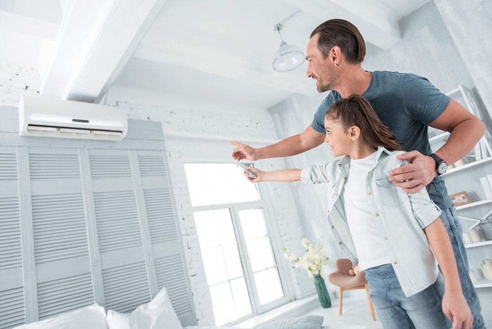 A Man And A Girl Are Adjusting The Air Conditioner — Jordan Wheatland Air Conditioning & Refrigeration In Dubbo, NSW