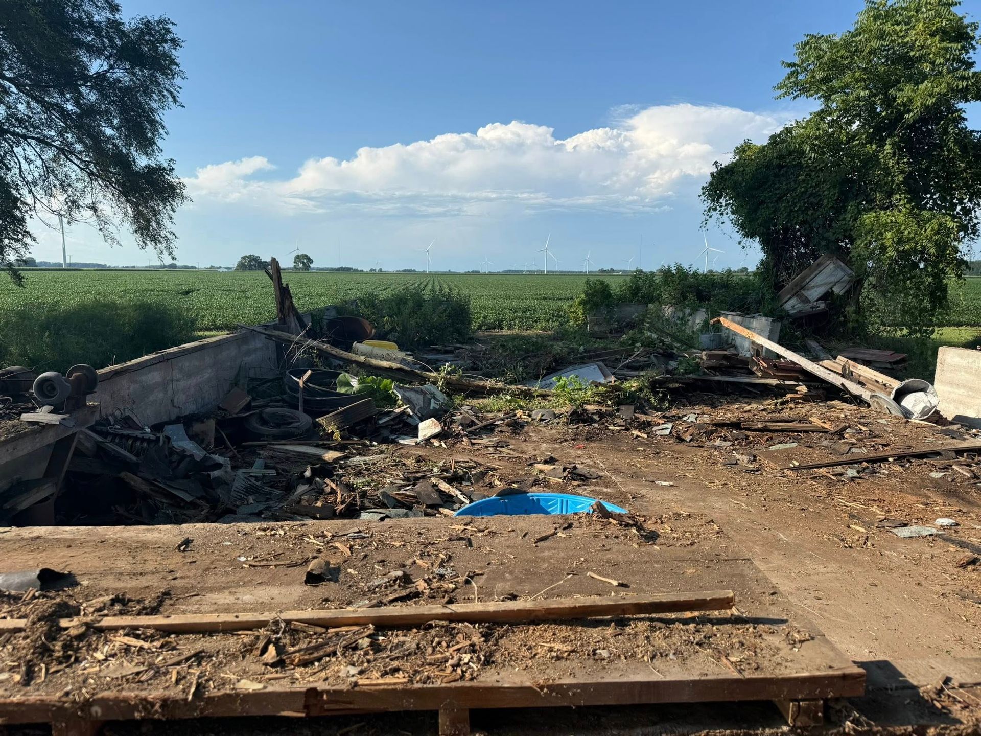 Debris and scattered wreckage in a field with a cloudy sky.