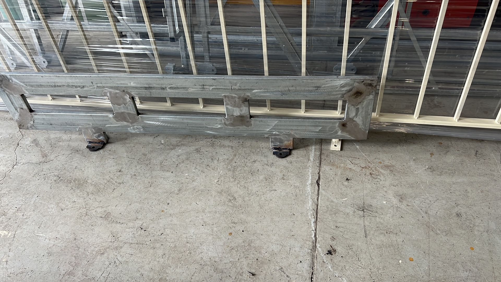Ruote di metallo per barricate appoggiate su un pavimento di cemento accanto a un cancello sbarrato.