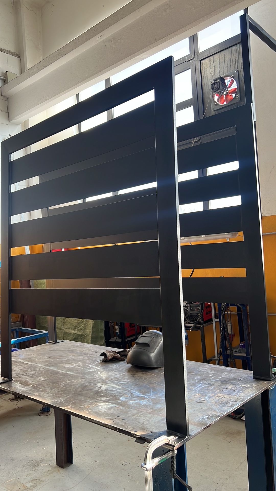 Pannelli divisori a doghe nere su un banco da lavoro in metallo in un'officina o studio luminoso.