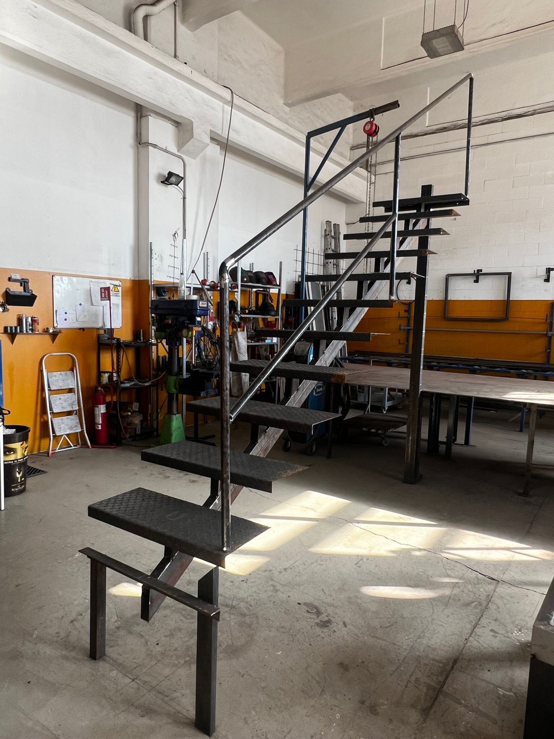 Scala in metallo nero con pianerottolo, ideale per un'officina o uno studio in stile industriale.