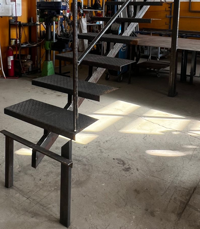 Due operai assemblano una grande struttura metallica su dei cavalletti in un'officina.