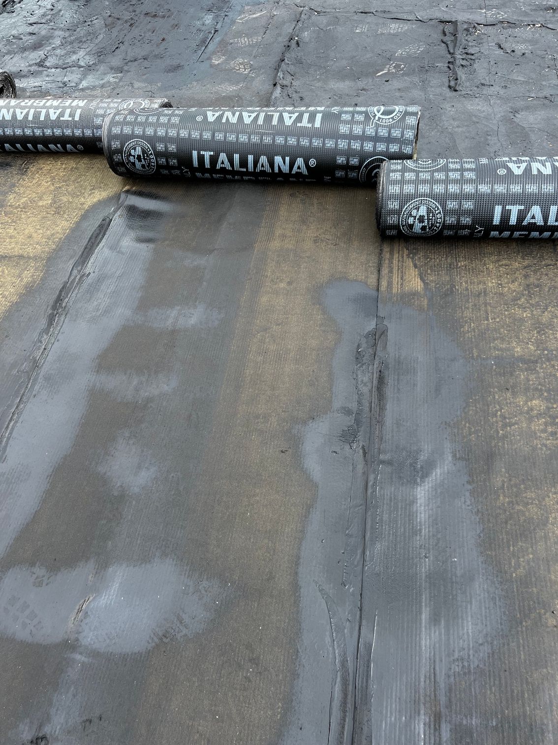 Materiale di copertura in rotoli su un tetto piano con giunture e rattoppi a vista.
