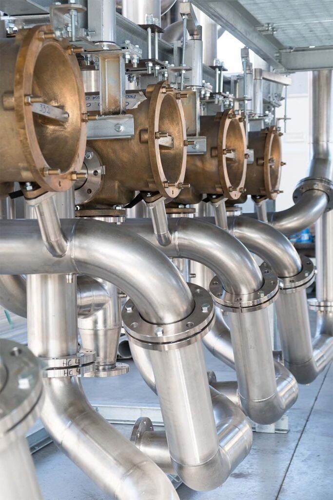 Tubazioni e macchinari industriali in acciaio inossidabile in un contesto di fabbrica.
