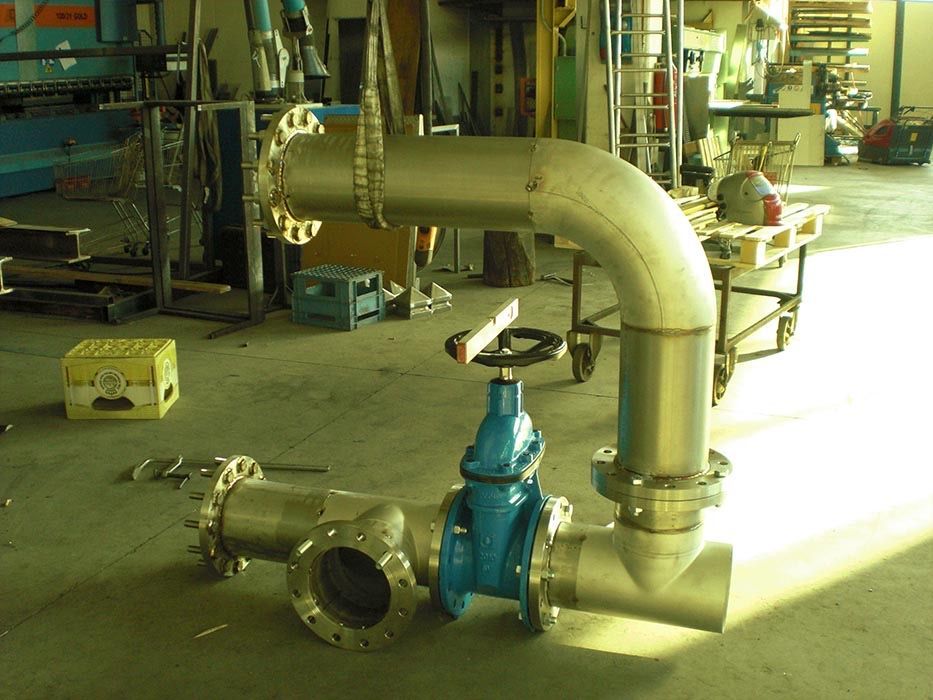 Assemblaggio di tubazioni industriali con valvola blu e grande gomito in un'officina.