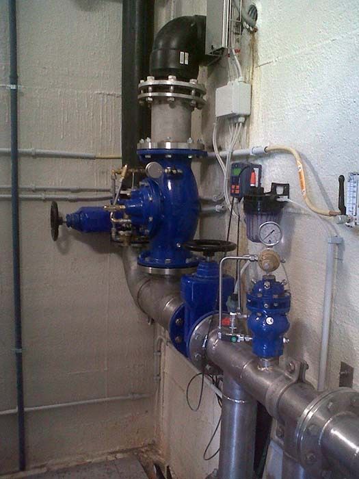 Tubi e valvole industriali blu montati a parete in un locale di servizio.