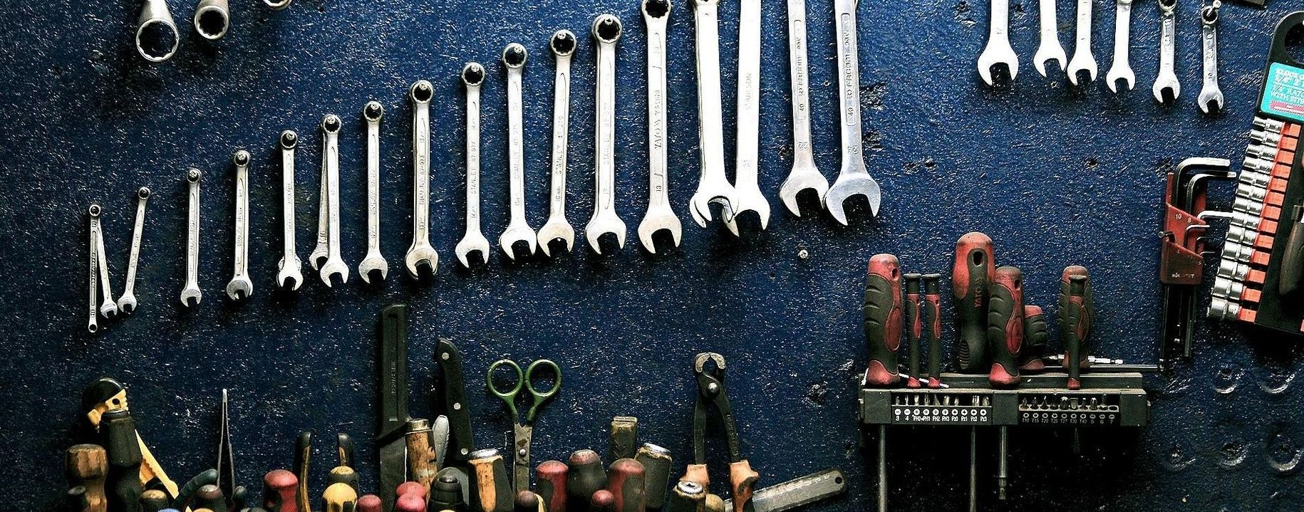 A bunch of tools are hanging on a wall in a garage