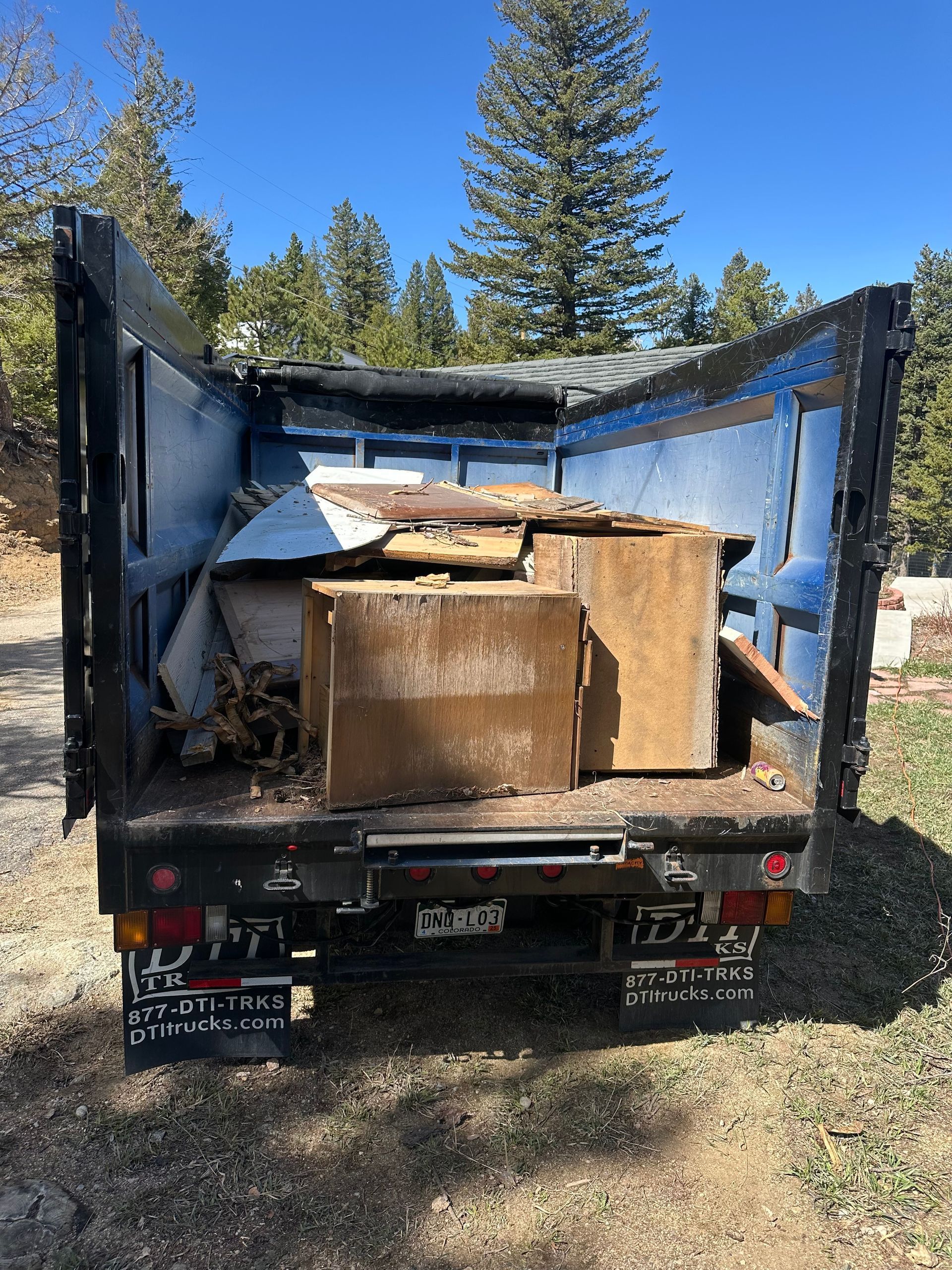 The back of a dump truck is filled with wooden boxes.