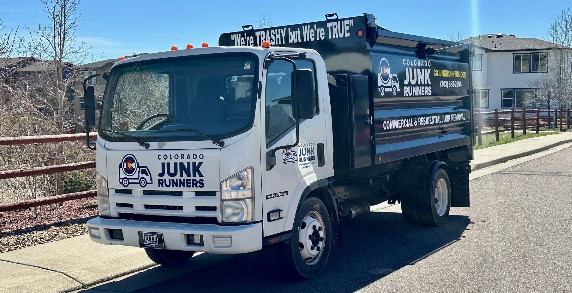 A junk truck is parked on the side of the road.