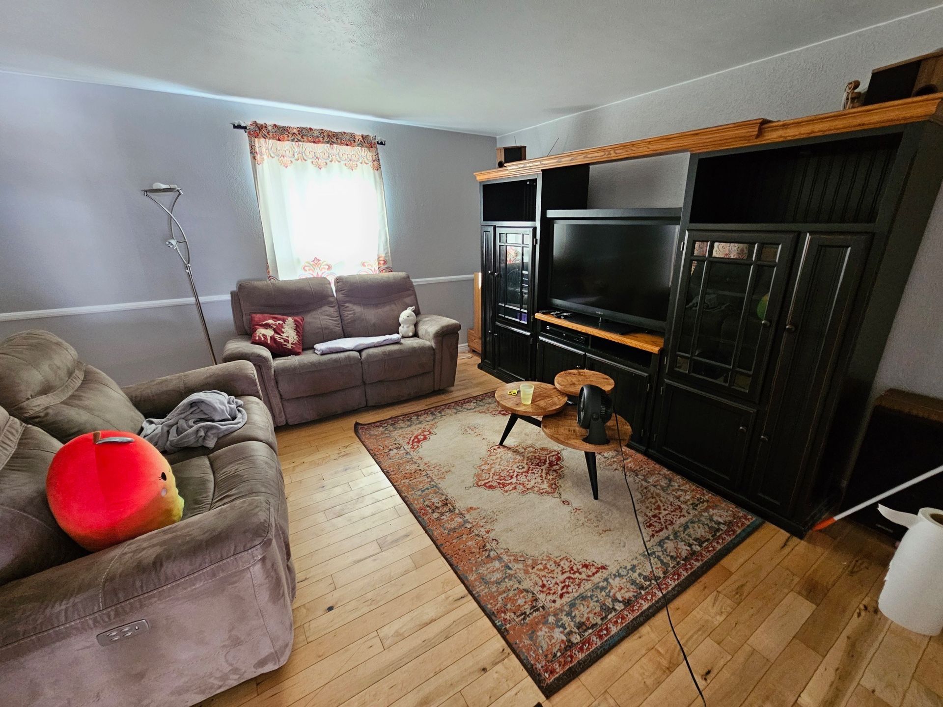 Living room with a large black entertainment center, two sofas, and an area rug.