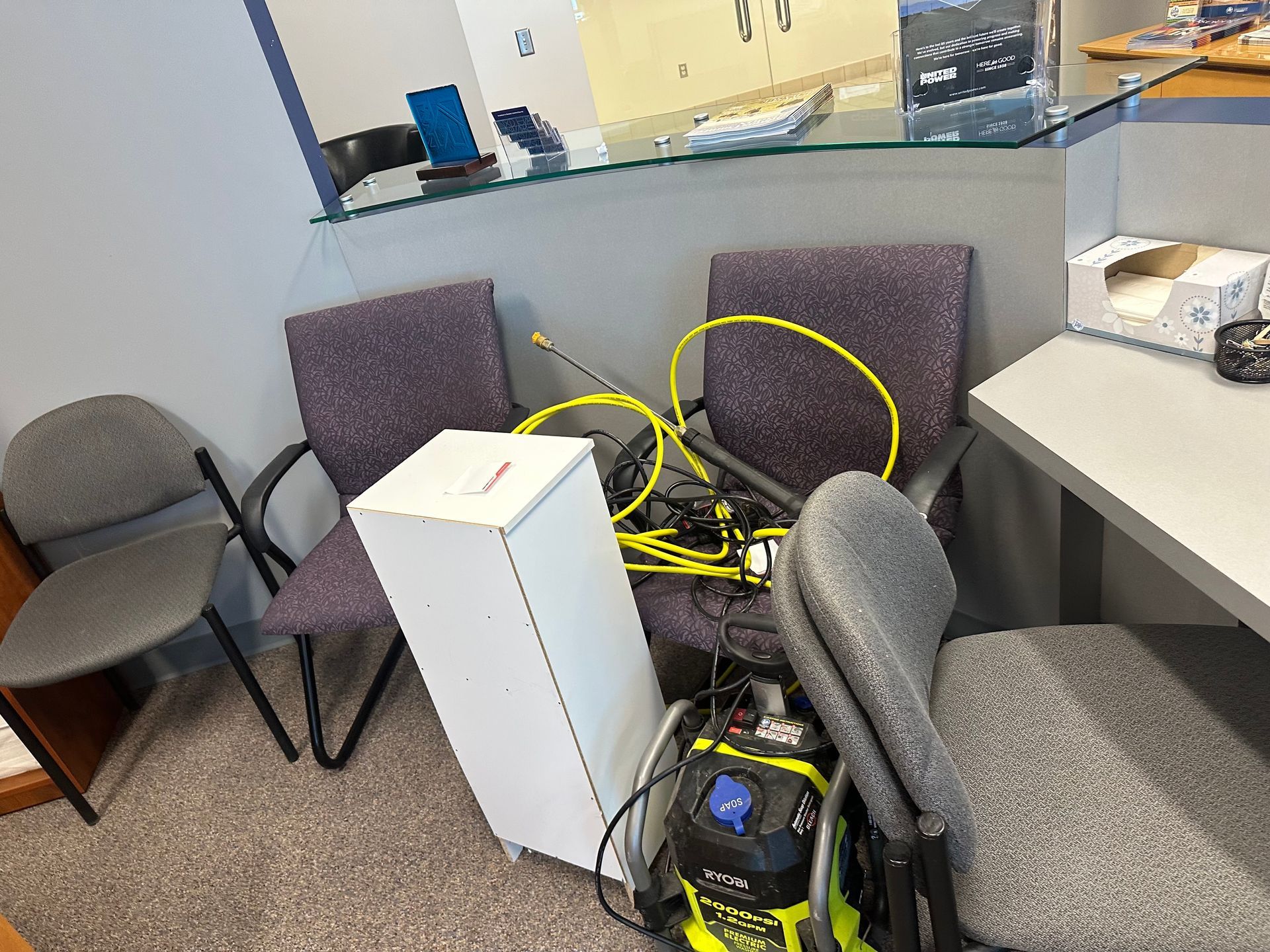Cluttered office area with chairs, a white box, and a vacuum cleaner.