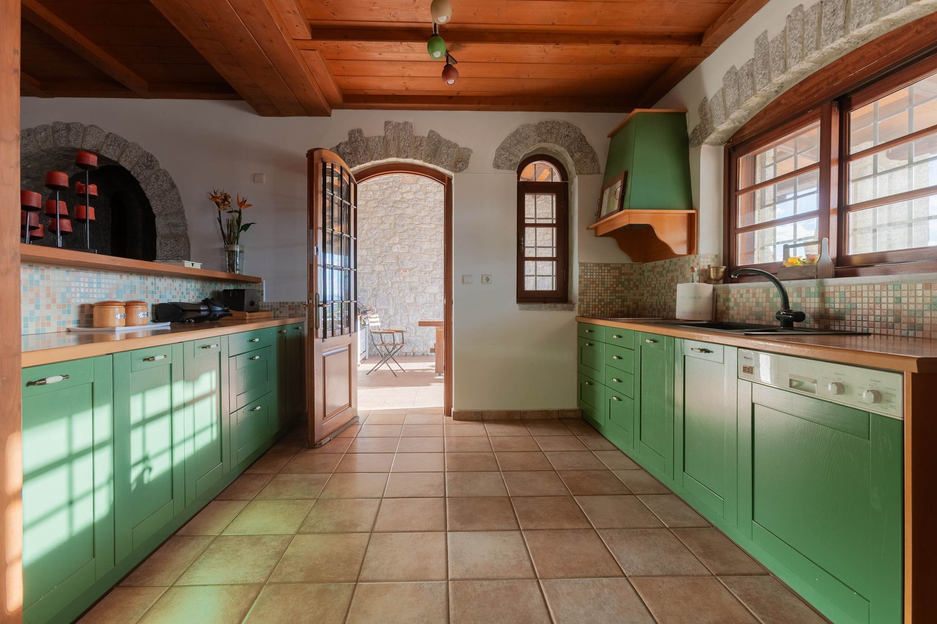 Green kitchen with patterned window light in a stone holiday residence