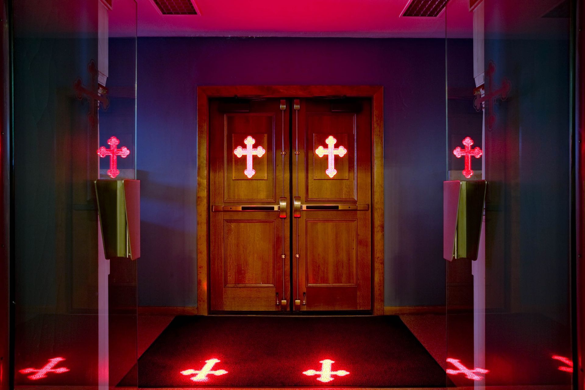Red cross-shaped light projections across a church entrance