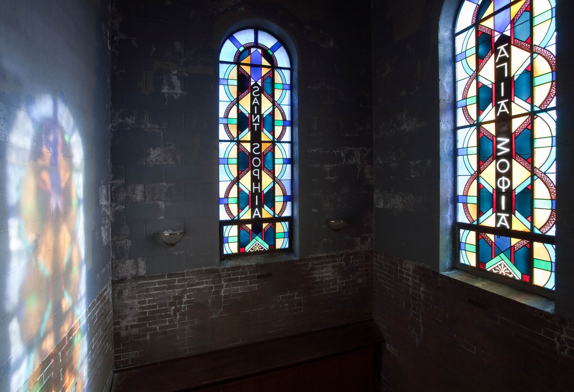 Prismatic stained-glass light cast across dark masonry walls